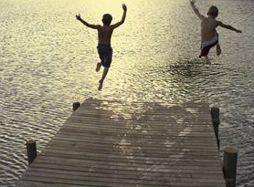 boys jumping off a pier into a pond